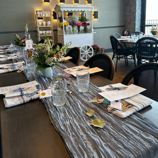A long dining table set for a special event with floral centerpieces and place settings.