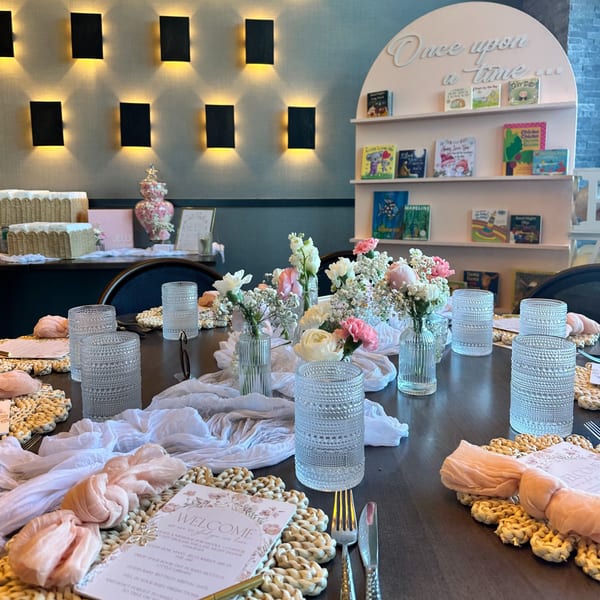 A beautifully set table at Hilltop Kitchen & Bar with floral centerpieces, glasses, and welcome cards.