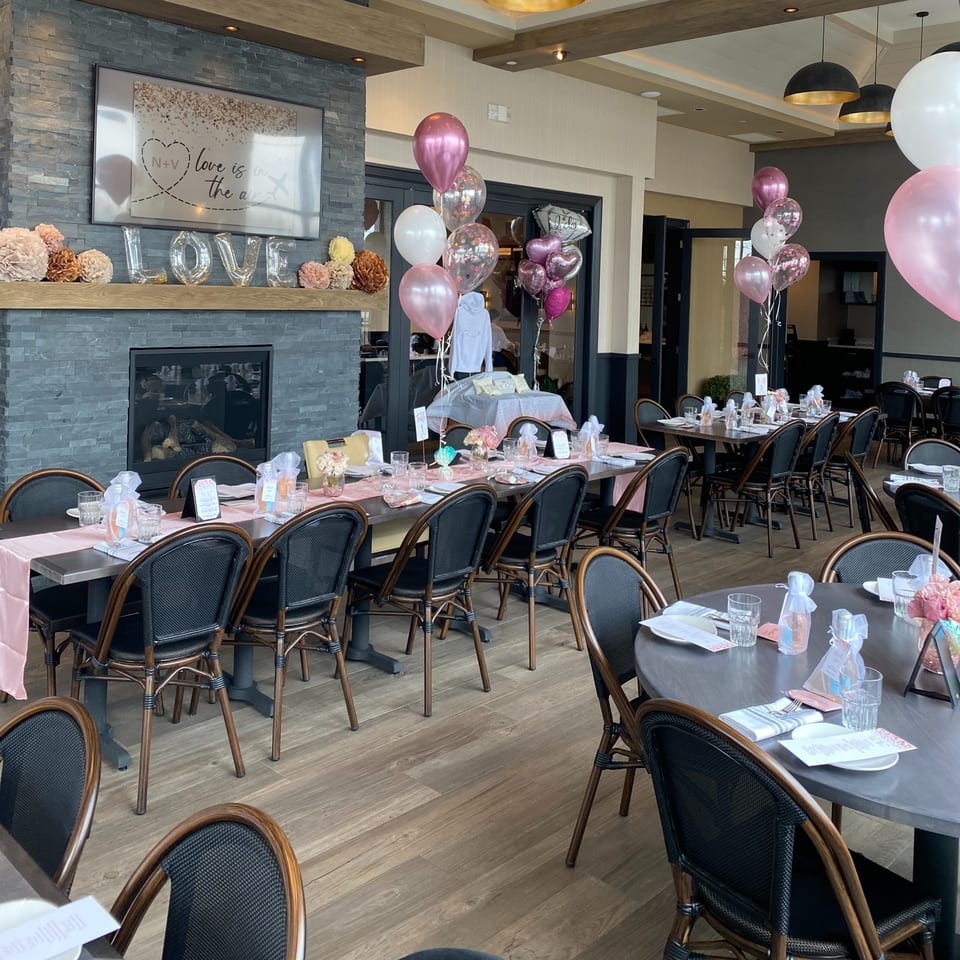 Hilltop Kitchen & Bar dining room set for a celebration with pink and white balloons and "LOVE" letters.