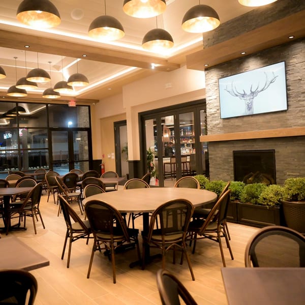 Interior of Hilltop Kitchen & Bar with tables, chairs, fireplace, and a bar area visible through glass doors.